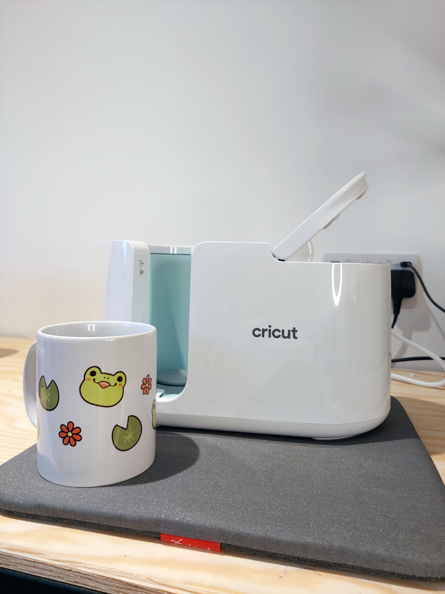 Emotions of a Frog 11oz Mug - EmilsDoodles
A photo showing how the design is applied to the mug. Which is a cricut mug press. Next to it is the frog mug.