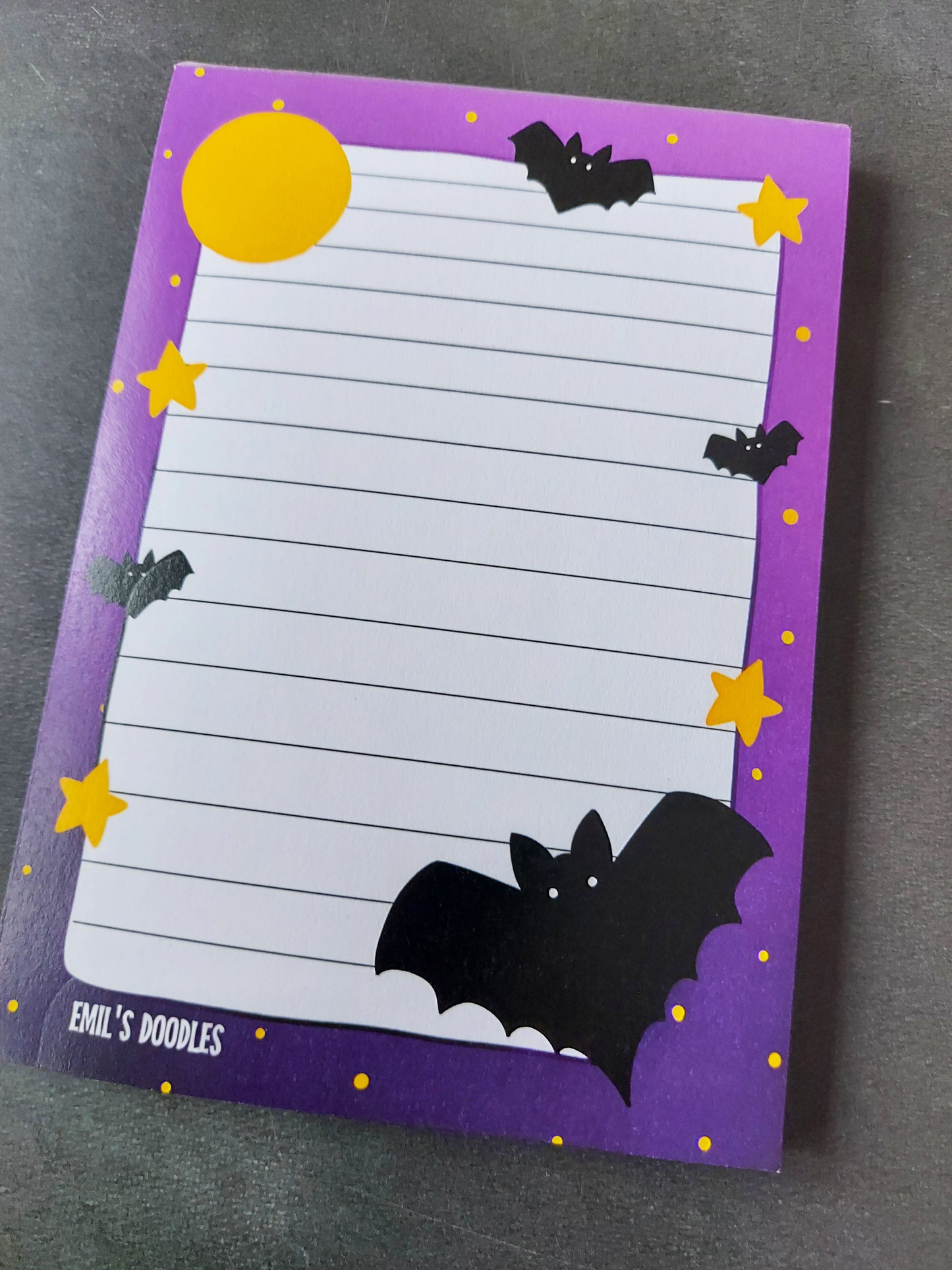 Bats Memo Pad - EmilsDoodles
On a grey background is a purple memo pad, with bats and stars around the border of the writable area. On the bottom right is a large bat. And in the top left is a yellow moon.