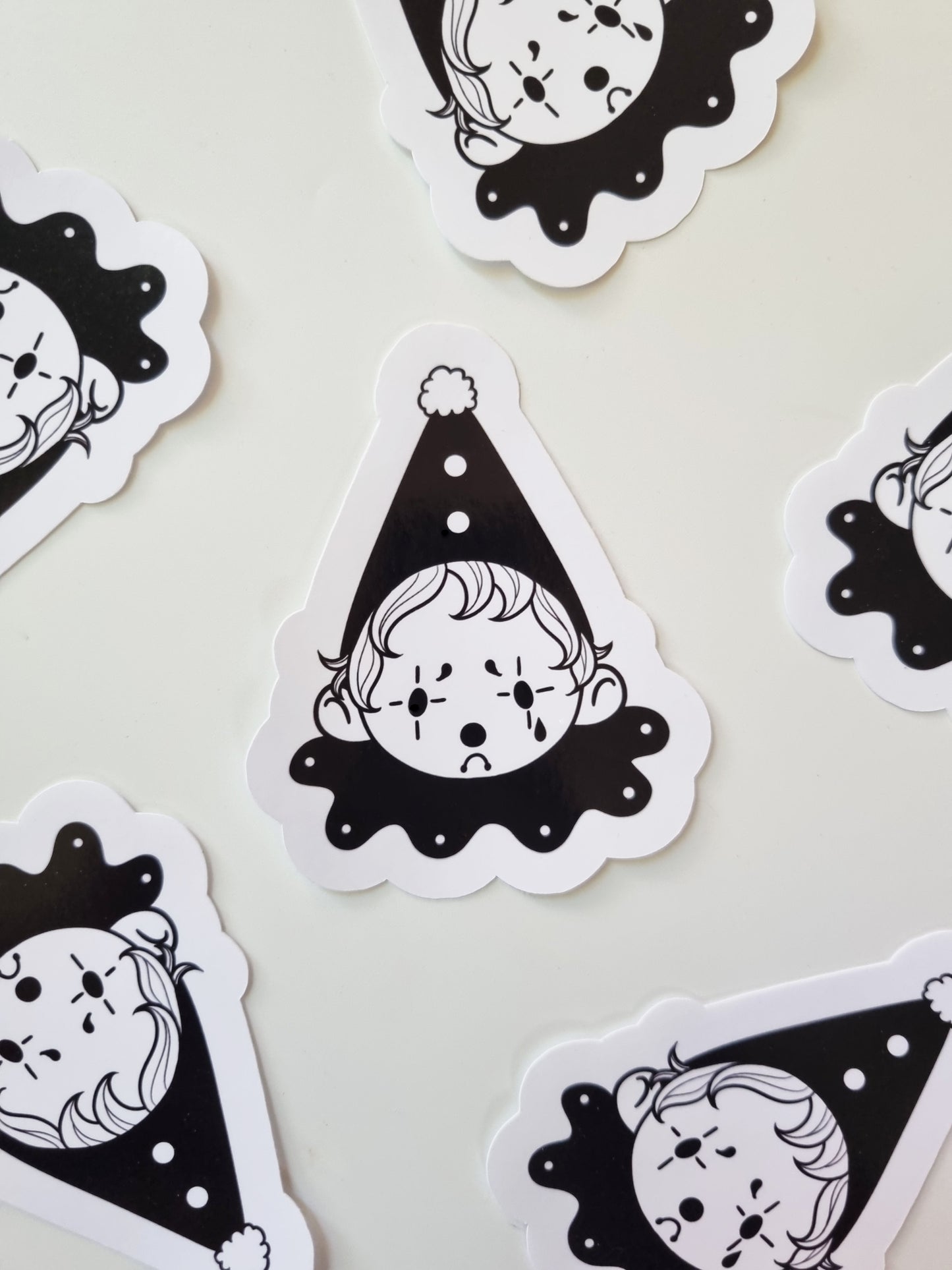 The Sad Clown | Glossy Clown Sticker - EmilsDoodles
On a white background are scattered black and white sad clown stickers.