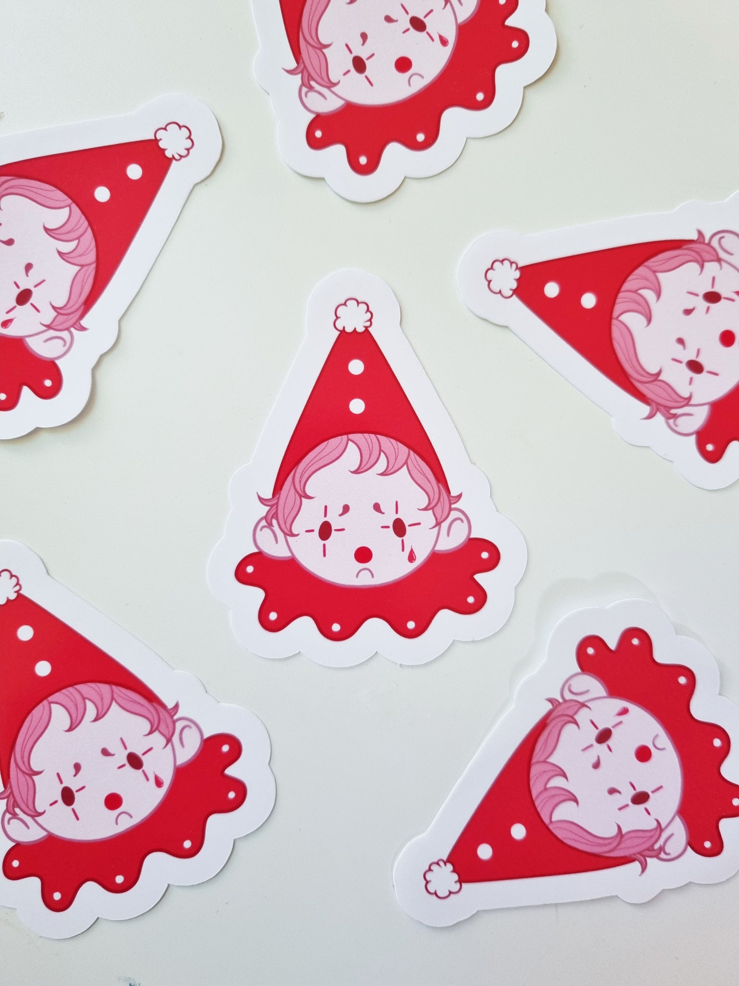 The Sad Clown | Glossy Clown Sticker - EmilsDoodles
On a white background, are pink monochrome sad clown stickers scattered around.