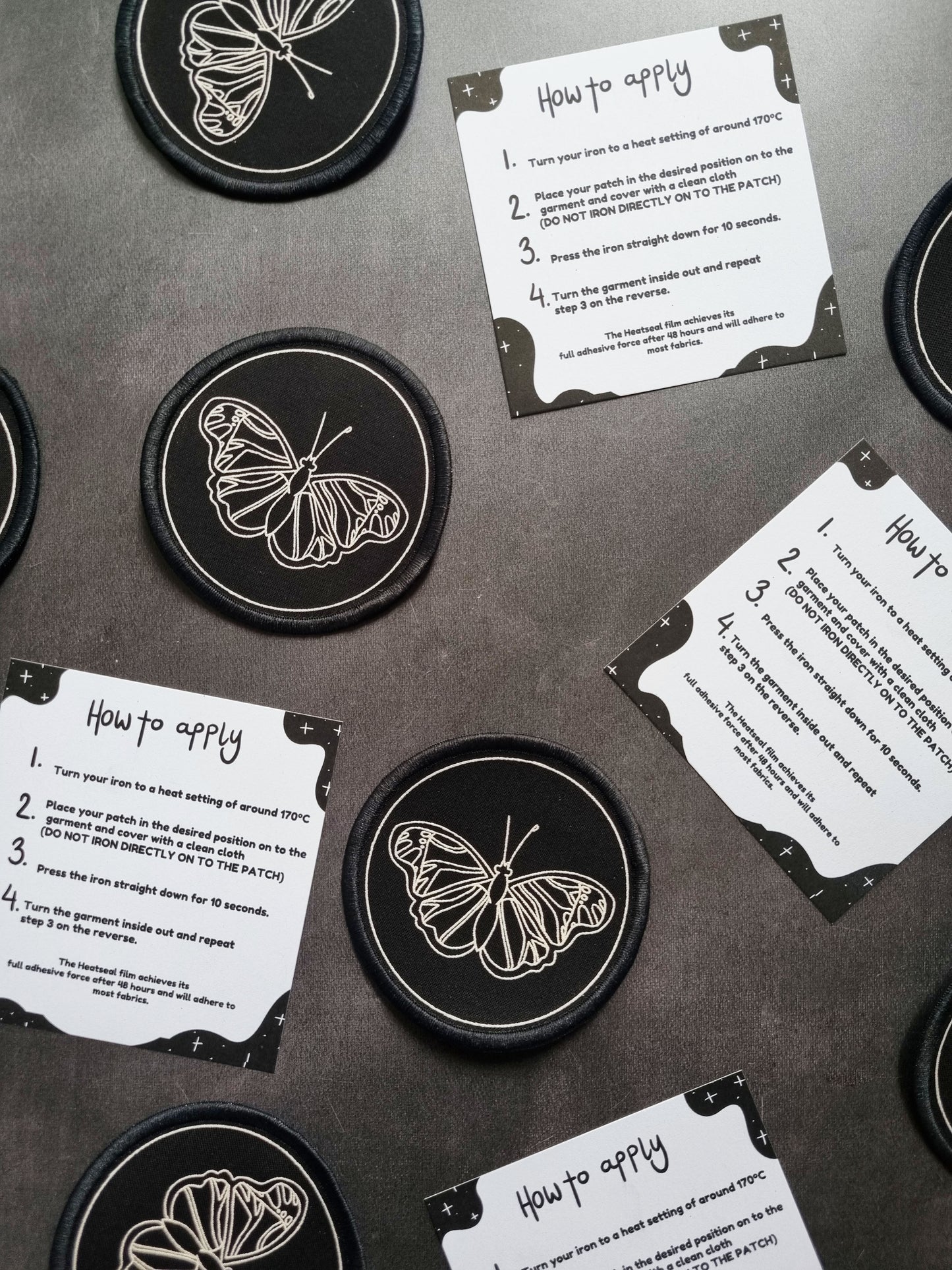 Butterfly Iron-on Patch - EmilsDoodles
On a grey background are circler, black patches with a butterfly printed in white ink. In an alternating pattern next to them is an instruction sheet.