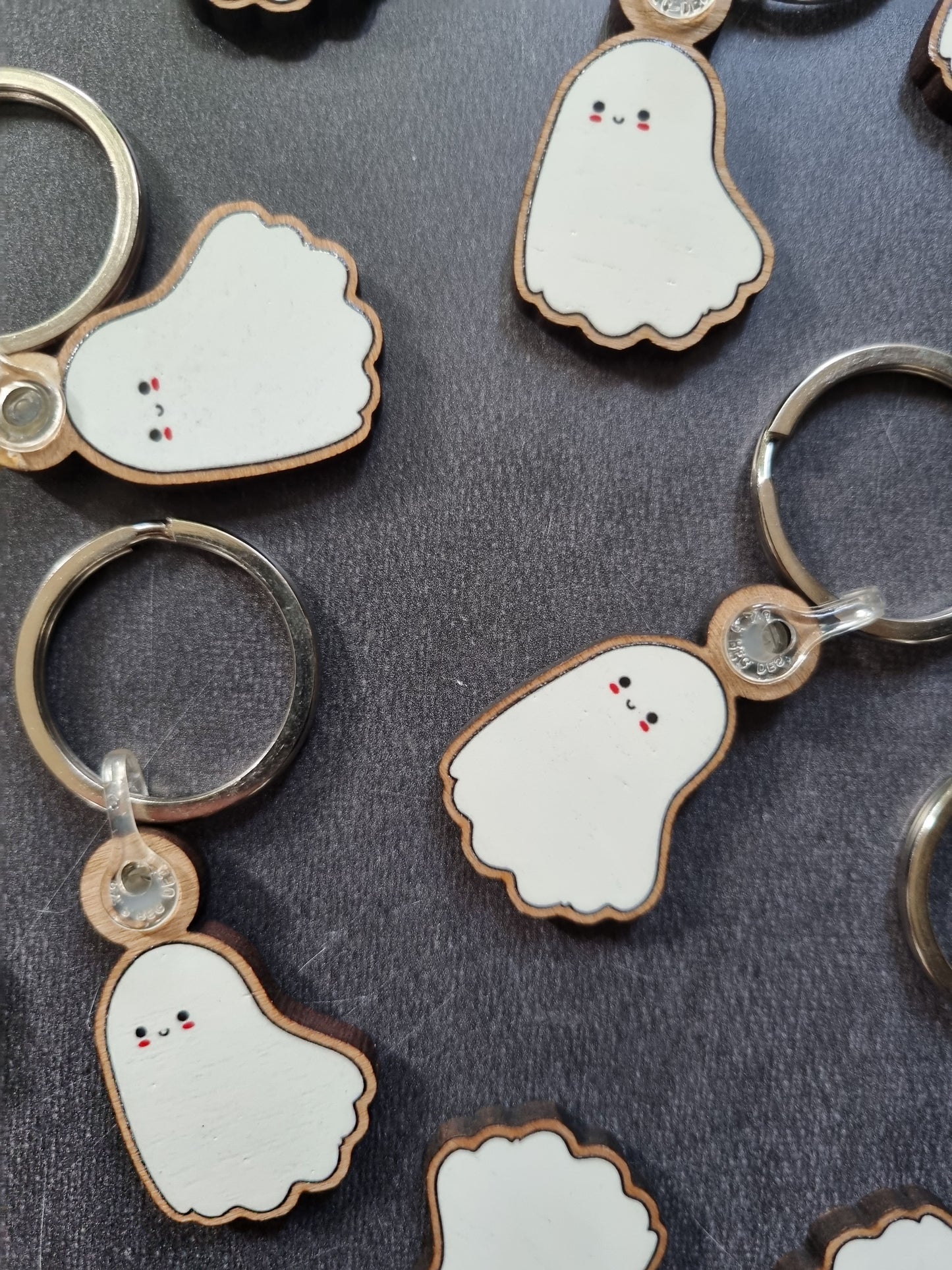 On a grey background, multiple ghost keyrings are scattered in a random fashion.