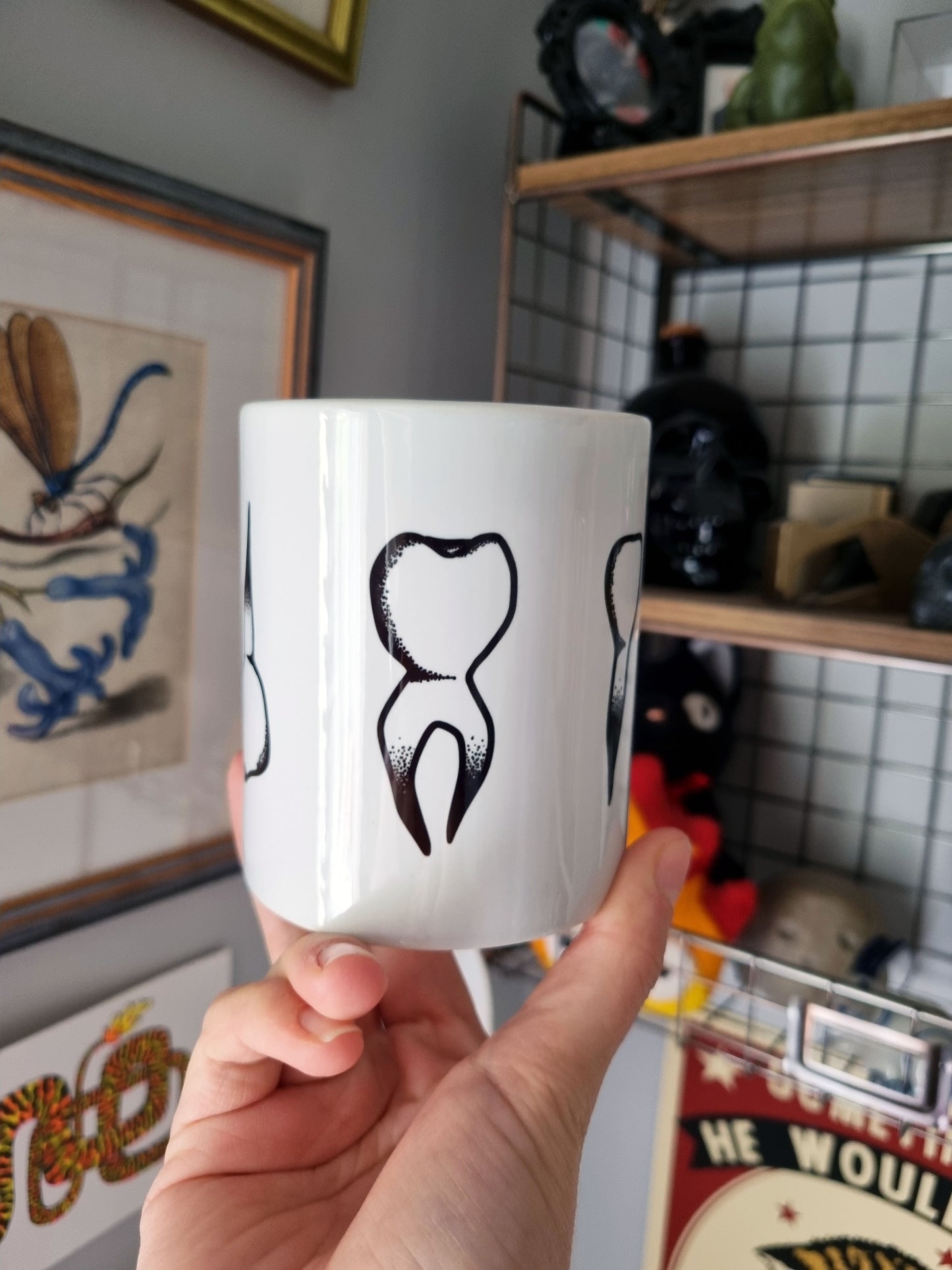 Teeth Teeth Teeth 11oz Mug - EmilsDoodles
A hand holding the mug. In the centre of the mug is a molar tooth design.
