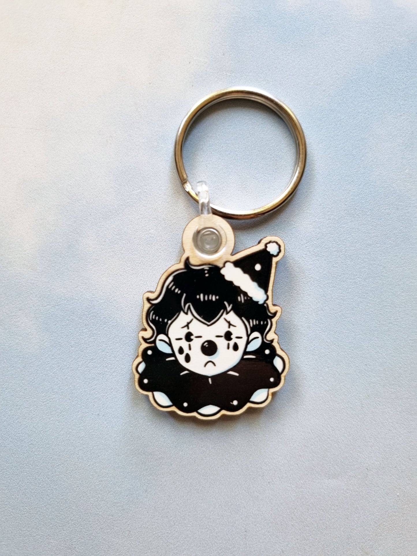 On a sky background is a single sad clown keyring.