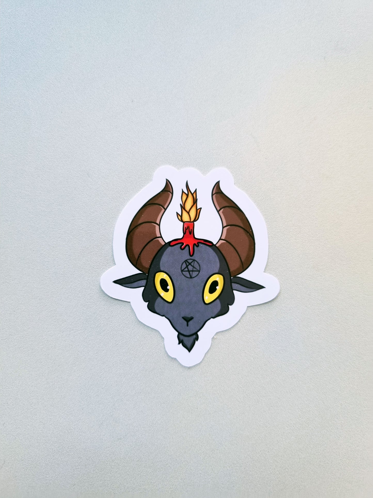 A sticker of Baphomet on a grey background.