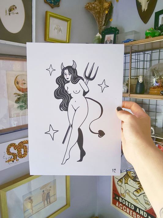 A hand is holding an A4 art print. The print features a naked woman with horns and a tail, holding a pitchfork behind her back. Around her are three stars. The print is monochrome apart  from some blush on are nose. The style of the art is semi-realistic. 