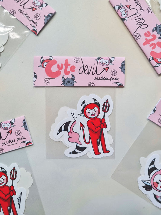 A sticker pack with a pink header made from card that reads "Cute Devil". The front sticker is a cute - chibi devil holding a pitchfork.