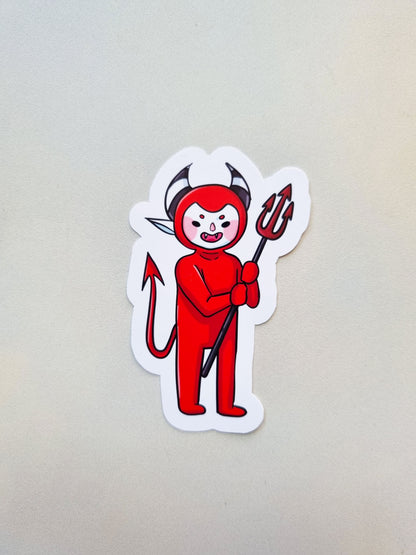 Sticker of a red devil character with horns and a pitchfork on a light gray background
