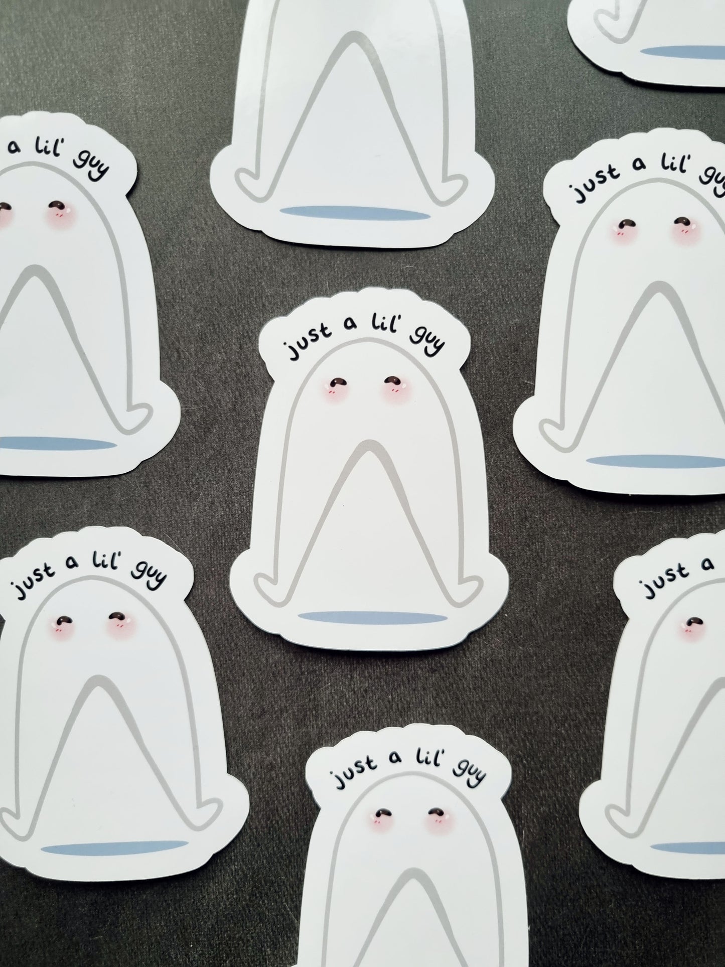 Several stickers on a grey background. The stickers are the fresno nightcrawler in a cute style with the phrase "just a lil' guy." above it.