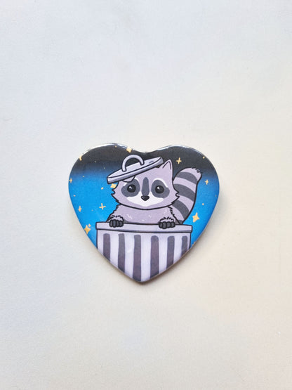 Heart-shaped button with a raccoon design on a white background